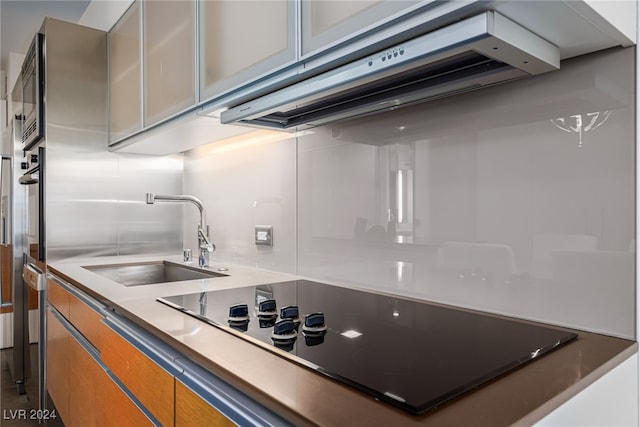 kitchen featuring exhaust hood, black electric cooktop, and sink