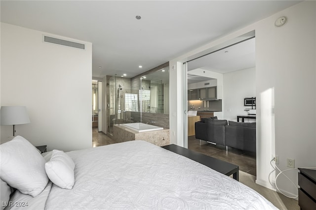 bedroom featuring ensuite bath and dark tile patterned flooring