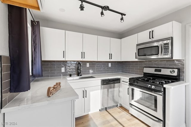 kitchen featuring white cabinets, sink, backsplash, and appliances with stainless steel finishes