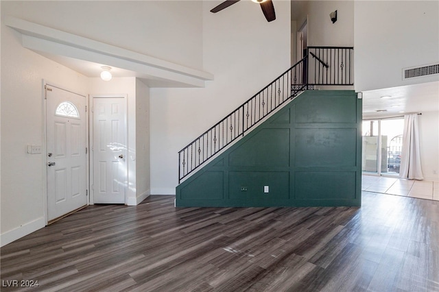 foyer entrance featuring a towering ceiling, dark wood-type flooring, and ceiling fan