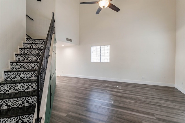 staircase featuring ceiling fan, hardwood / wood-style flooring, and a high ceiling