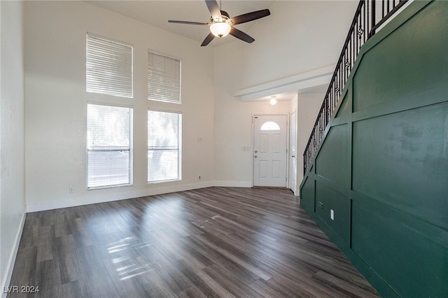 entryway with dark hardwood / wood-style flooring, ceiling fan, and a towering ceiling