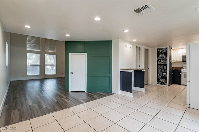 kitchen with white cabinetry, light hardwood / wood-style flooring, and white range oven