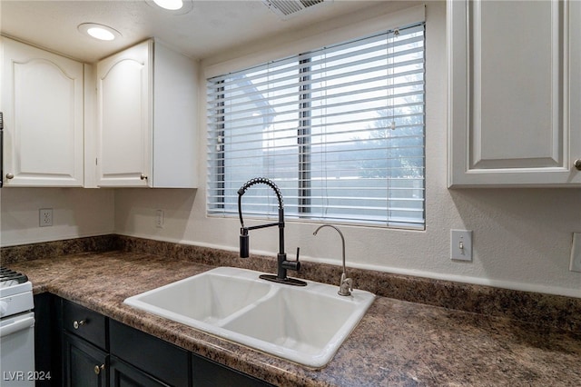 kitchen with white range oven, white cabinetry, and sink