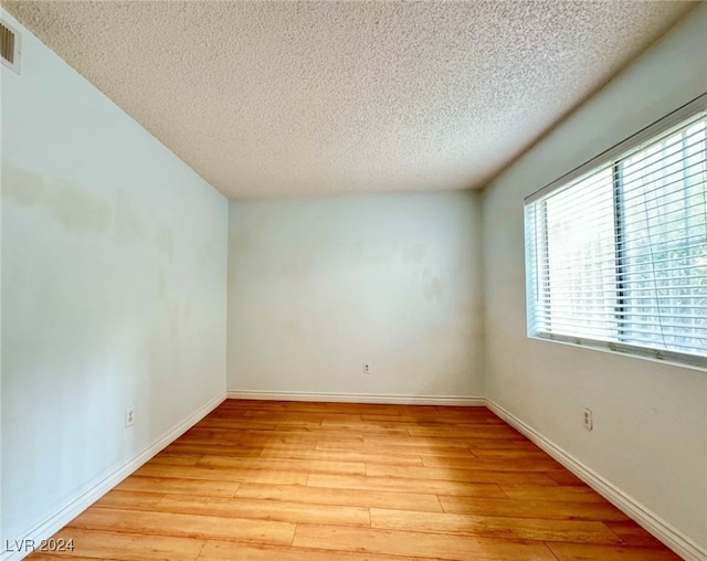 spare room with a textured ceiling and light hardwood / wood-style flooring