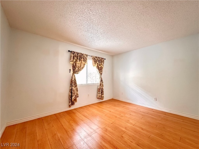 unfurnished room with a textured ceiling and light hardwood / wood-style floors