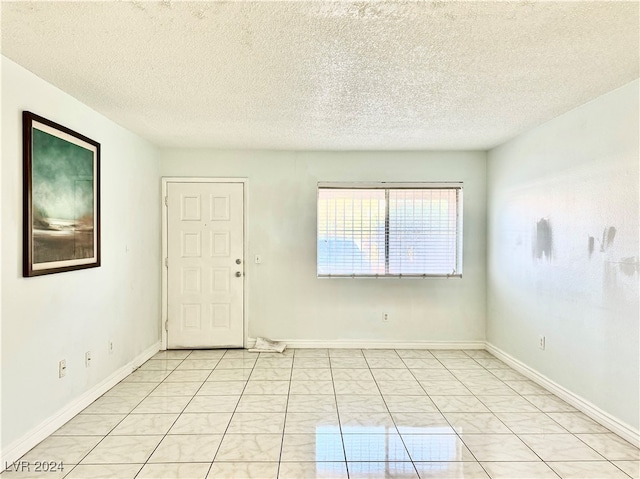 unfurnished room with a textured ceiling and light tile patterned floors