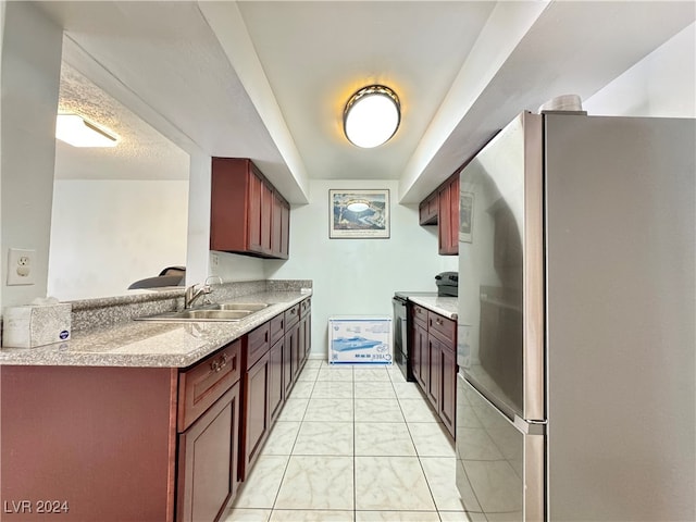 kitchen with black / electric stove, sink, light stone counters, and stainless steel fridge