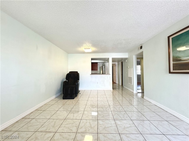 tiled empty room with a textured ceiling