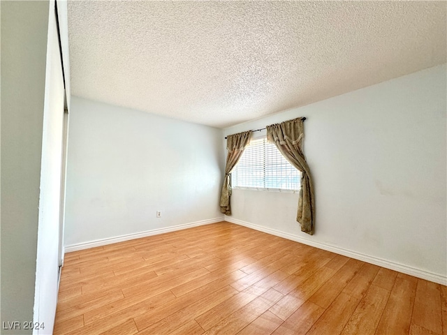 unfurnished room with light hardwood / wood-style flooring and a textured ceiling