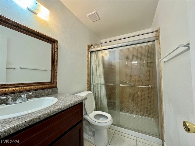 bathroom with tile patterned flooring, vanity, toilet, and a shower with shower door