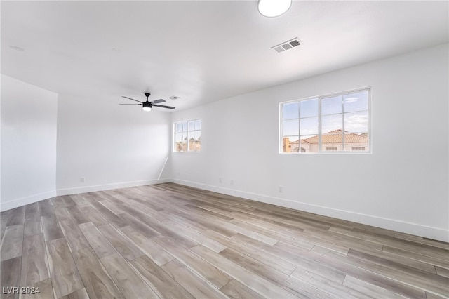 spare room featuring light wood-type flooring, plenty of natural light, and ceiling fan