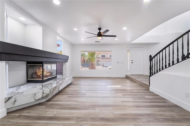 unfurnished living room featuring light wood-type flooring, a fireplace, and ceiling fan