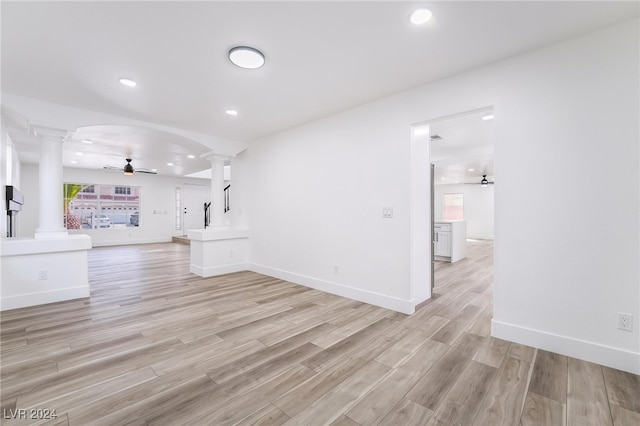 unfurnished living room with ornate columns, ceiling fan, and light hardwood / wood-style flooring