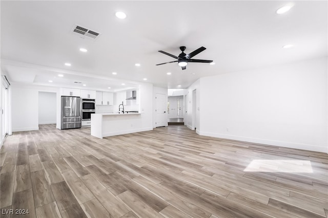 unfurnished living room with ceiling fan, sink, and light hardwood / wood-style floors