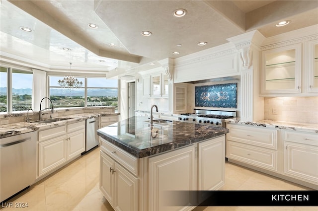 kitchen featuring stainless steel appliances, a center island with sink, a chandelier, tasteful backsplash, and sink