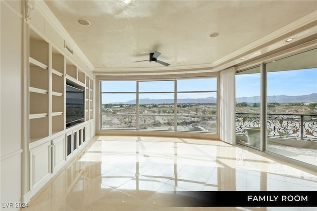 unfurnished sunroom featuring ceiling fan and a mountain view