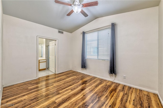 unfurnished bedroom featuring ceiling fan, connected bathroom, wood finished floors, visible vents, and vaulted ceiling