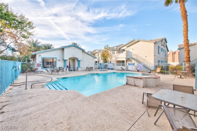 pool featuring a community hot tub, a patio area, fence, and a residential view