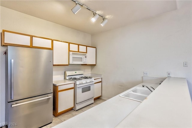 kitchen featuring white appliances, light countertops, white cabinetry, a sink, and light tile patterned flooring