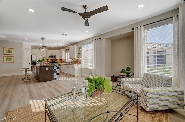 dining room featuring a wealth of natural light, ceiling fan with notable chandelier, and light wood-type flooring