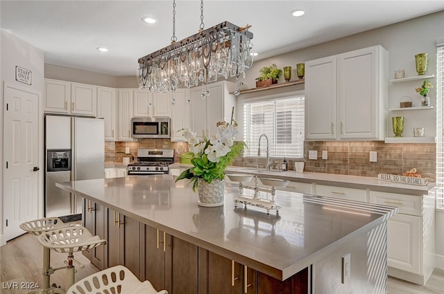 kitchen with white cabinets, appliances with stainless steel finishes, light hardwood / wood-style floors, and a center island