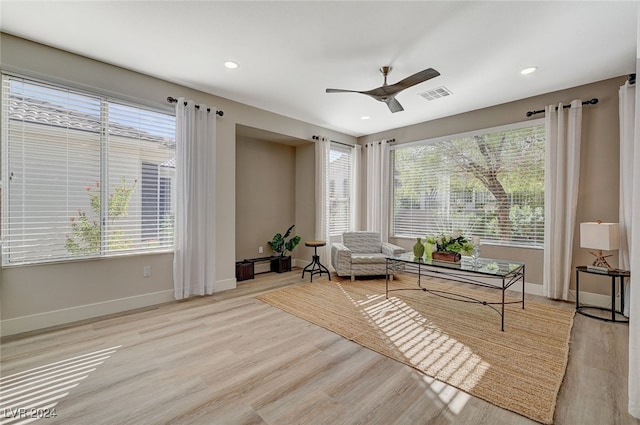 living area with light wood-type flooring, ceiling fan, and a healthy amount of sunlight