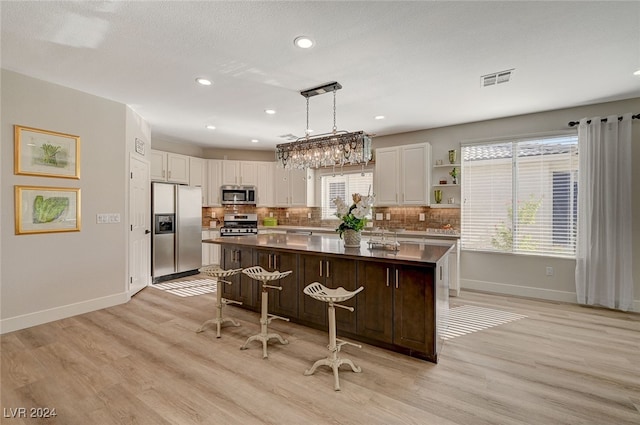 kitchen with light hardwood / wood-style flooring, a kitchen island, decorative backsplash, and stainless steel appliances