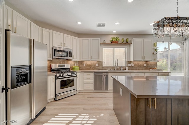 kitchen with white cabinets, a chandelier, a healthy amount of sunlight, and appliances with stainless steel finishes