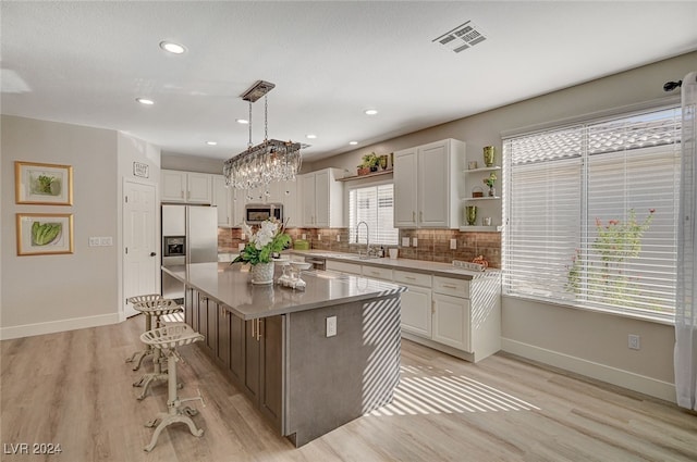 kitchen featuring a kitchen island, white cabinetry, appliances with stainless steel finishes, and decorative light fixtures