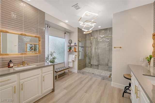 bathroom with vanity, an enclosed shower, decorative backsplash, hardwood / wood-style flooring, and a chandelier