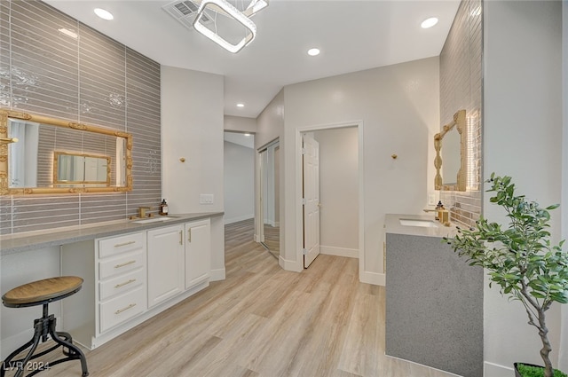 interior space with sink, light hardwood / wood-style floors, and white cabinets