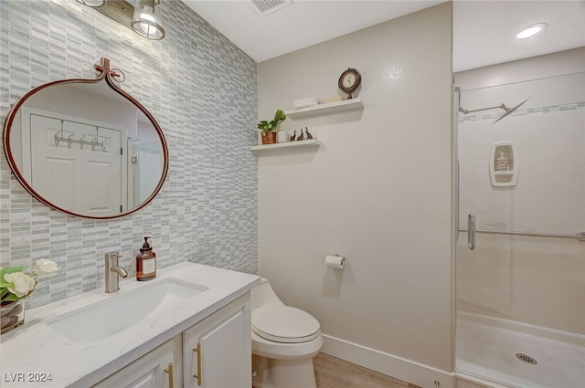 bathroom featuring tasteful backsplash, wood-type flooring, vanity, an enclosed shower, and toilet