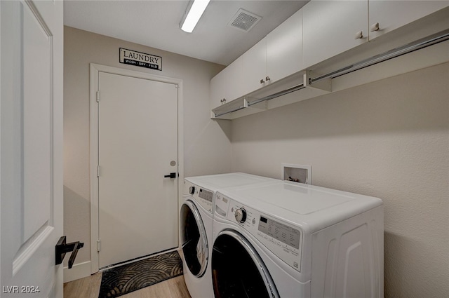 laundry room with cabinets, light wood-type flooring, and independent washer and dryer