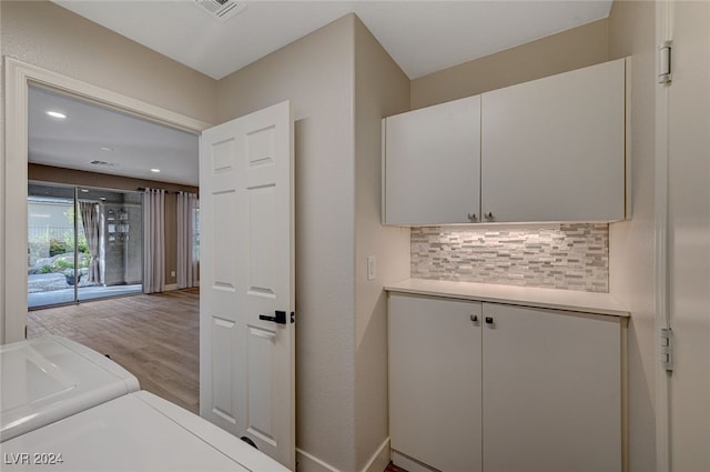 clothes washing area with cabinets, washer and dryer, and light hardwood / wood-style floors