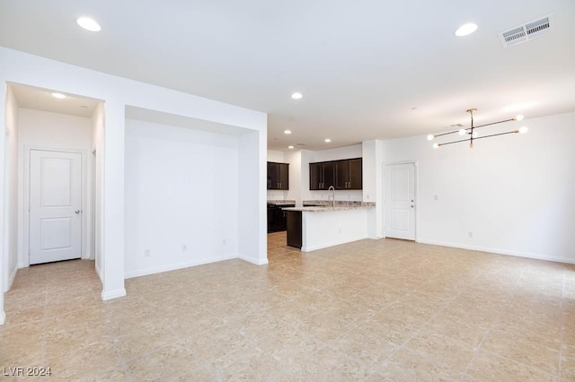 unfurnished living room featuring sink and an inviting chandelier