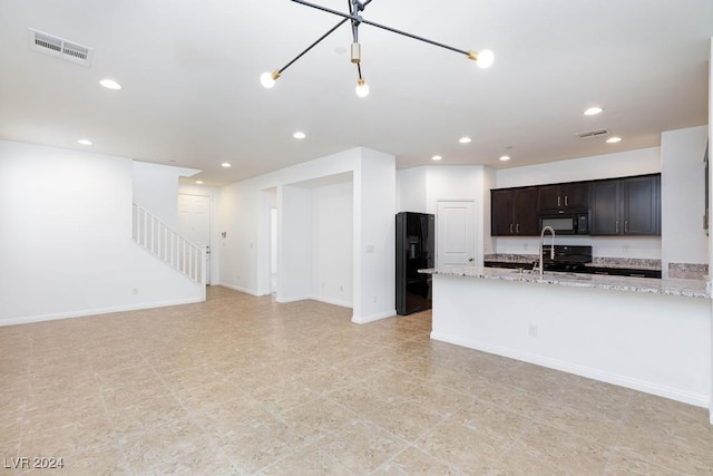 kitchen with black appliances, dark brown cabinets, sink, and light stone counters