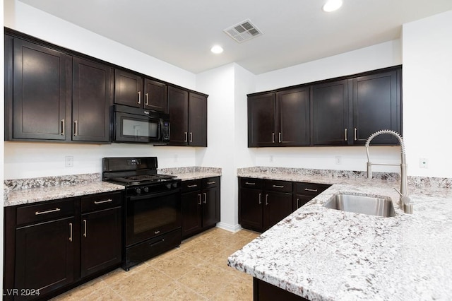 kitchen with light stone counters, black appliances, sink, light tile patterned flooring, and dark brown cabinets