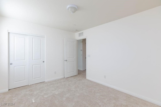 unfurnished bedroom featuring light colored carpet and a closet