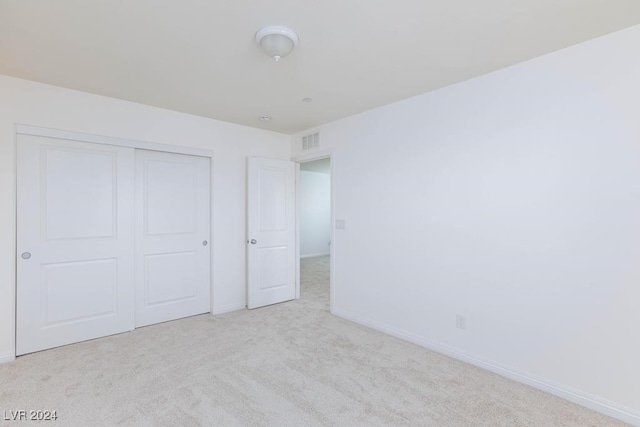 unfurnished bedroom featuring light colored carpet and a closet