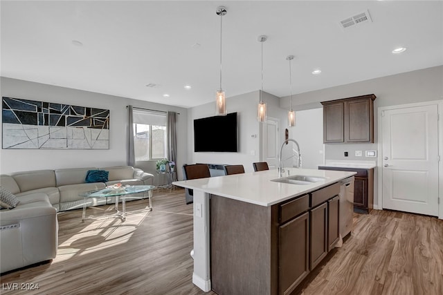 kitchen featuring dark brown cabinetry, light hardwood / wood-style floors, sink, and an island with sink