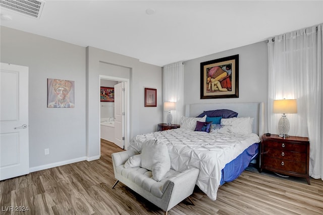 bedroom with light hardwood / wood-style floors and connected bathroom