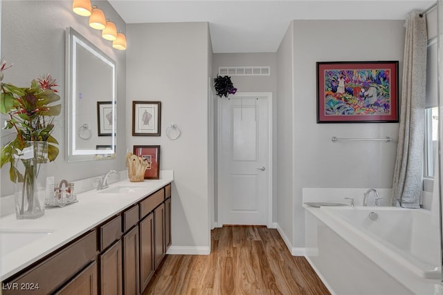 bathroom featuring vanity, hardwood / wood-style flooring, and a tub