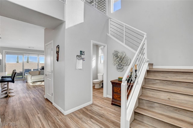 staircase with a towering ceiling and wood-type flooring