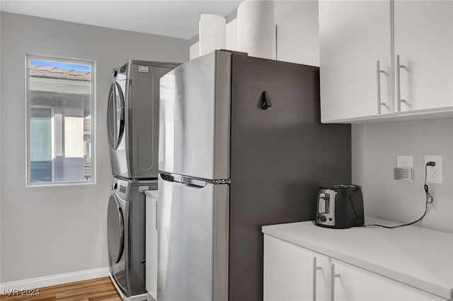 laundry room featuring wood-type flooring and stacked washer / dryer