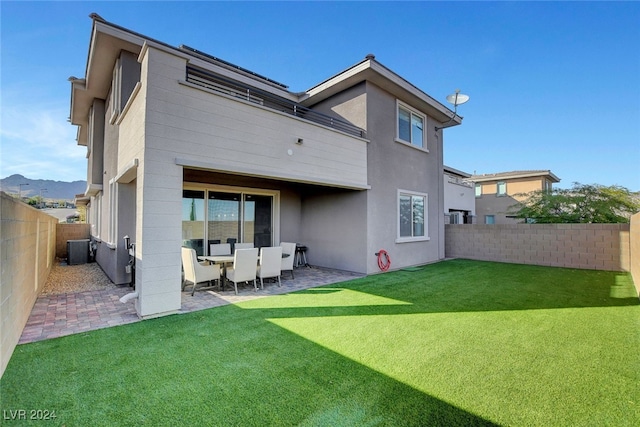 rear view of house with central AC, a mountain view, a patio, and a yard