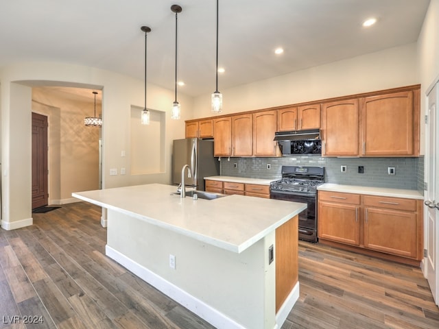 kitchen featuring dark hardwood / wood-style flooring, black gas range, sink, an island with sink, and pendant lighting