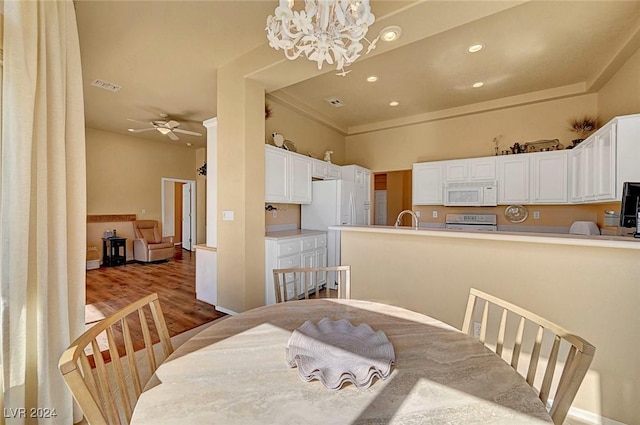 dining area with sink, ceiling fan with notable chandelier, and hardwood / wood-style flooring