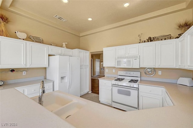 kitchen with white appliances, white cabinetry, and sink