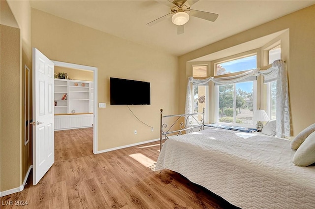 bedroom featuring ceiling fan, light hardwood / wood-style floors, and a walk in closet